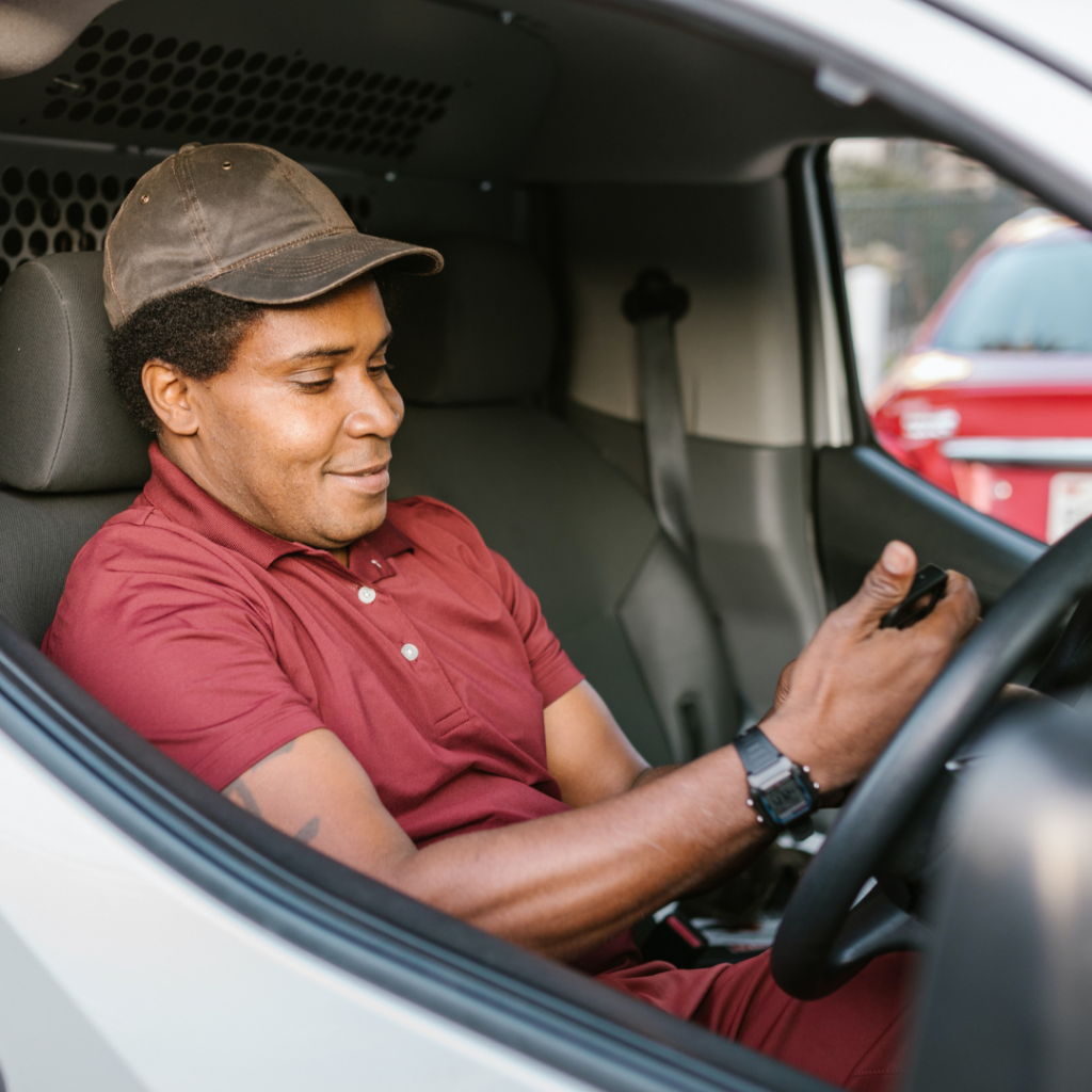 Happy delivery driver using his phone.